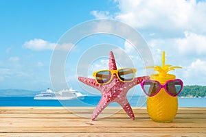 Summer vacation concept with cute starfish and pineapple juice with sunglasses over sea beach background