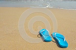 Tropical summer vacation concept. Flipflops on a sandy ocean beach. Blue beach shoes on the sandy seashore.