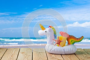 Summer vacation concept with orange juice and unicorn pool float over sea beach background