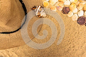 Summer vacation concept with seashells, women`s beach hat and sunglasses on sand background. Flat lay, top view