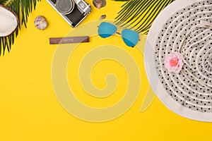 Summer vacation concept. stylish sunglasses, retro photo camera and green palm leaves on yellow background, flat lay