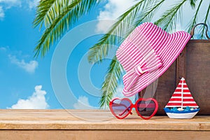 Summer vacation concept with suitcase, sunglasses, hat and boat over sea beach background