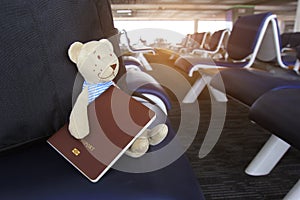 Summer vacation concept, Teddy bear with passport and traveling bag in the airport terminal