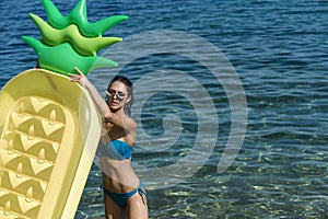 Summer vacation concept. Woman holds air mattress pineapple shaped with sea or ocean on background. Lady with air