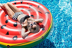 Summer Vacation. Enjoying suntan Woman in bikini on the inflatable mattress in the swimming pool