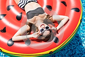 Summer Vacation. Enjoying suntan Woman in bikini on the inflatable mattress in the swimming pool