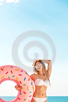 Summer Vacation. Enjoying suntan woman in white bikini with donut mattress near the swimming pool.