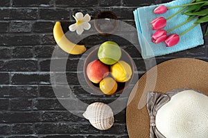 Summer vacation, fruit, tulip and sun hat in brick wall background,