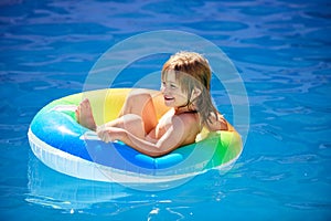 Summer vacation fun. Cute kid in swimming pool. Little child playing in blue water with floating ring.