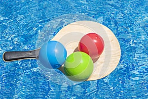 Summer vacation fun, water games, beach activity sport Balls on beach tennis racket float on blue water of swimming pool