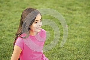 Summer vacation. Girl cute kid sit green grass. Emotional happy kid relaxing outdoors. What makes child happy. Vacation