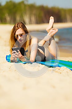 Summer vacation Girl with phone tanning on beach