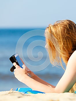 Summer vacation Girl with phone tanning on beach