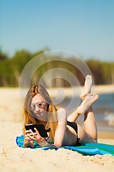 Summer vacation Girl with phone tanning on beach