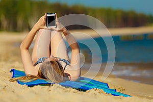 Summer vacation Girl with phone tanning on beach