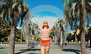 Summer vacation, happy cheerful young woman raising her hands up on palm tree background