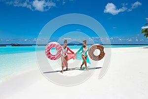 Summer Vacation. Happy free twoSummer Vacation. Happy free two women with donut float mattress. Girls wearing Chiffon Beach Dress