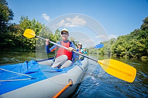 Summer vacation - Happy girl with her mother kayaking on river.