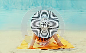 Summer vacation, happy relaxing young woman with straw hat lying on sand on the beach on sea background