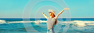 Summer vacation, happy smiling woman raising her hands up on the beach on sea background on sunny day