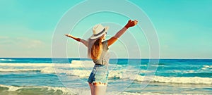 Summer vacation, happy smiling woman raising her hands up on the beach on sea background on sunny day