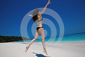 Summer vacation. Happy woman running and jumping on exotic beach