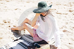 Summer vacation. Happy young boho woman relaxing and enjoying sunny warm day at ocean. Space for text. Stylish hipster girl in hat