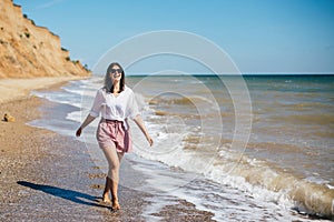 Summer vacation. Happy young boho woman walking and having fun in sea waves in sunny warm day on tropical island. Space for text.