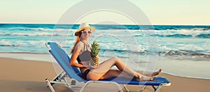 Summer vacation, happy young woman lying on deckchair with pineapple on beach on sea background