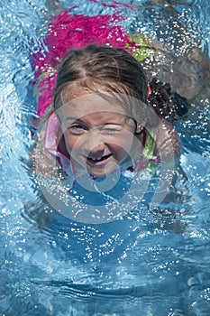 Summer vacation, healthy lifestyle and happy childhood concept. Top view of cute child girl having fun in swimming pool