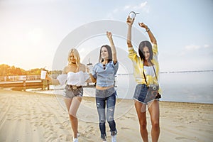 Summer vacation, holidays, travel and people concept - group of smiling young women dancing on beach.