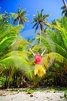 Summer Vacation and Lifestyle concept. Handsome Man travel in the tropical sandy beach on background palm, sea and blue summer sky