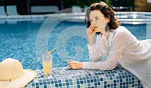 Summer vacation luxury serious woman near swimming pool of luxury spa resort or hotel. girl in a wet shirt lying on the