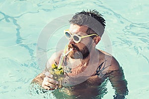 Summer vacation at Miami beach or Maldives. Pool party with hipster in blue water. Man swimming and drink alcoholic