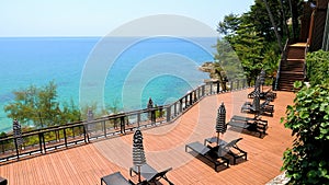 Summer vacation in modern resort. Empty sun lounges with umbrellas in luxury hotel with view on turquoise sea. Concept