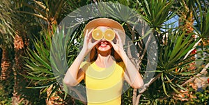 Summer, vacation, nutrition and vegetarian concept. Happy healthy cheerful young woman covering her eyes with slices of orange