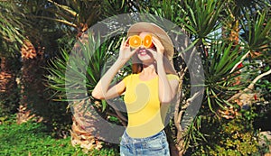 Summer, vacation, nutrition and vegetarian concept. Happy healthy cheerful young woman covering her eyes with slices of orange