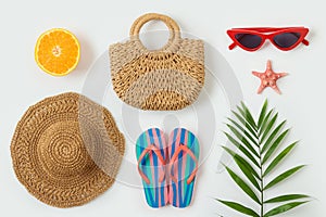 Summer vacation objects. Fashion bag beach hat, flip flops and palm tree leaf on white background. Top view from above