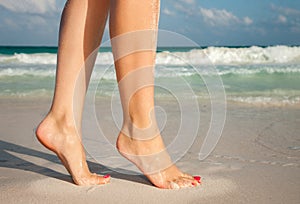 Closeup of woman legs walking on beach sand