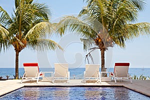Summer vacation at poolside. Veranda decorated with deck chairs with an ocean view