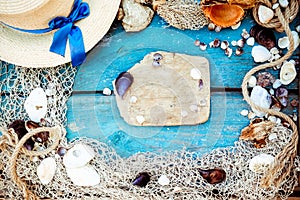 Summer vacation relaxation background theme with seashells, fishing net, hat, rope, stones and weathered wood blue background with
