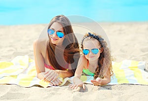 Summer vacation, relaxation, travel - portrait mother and child lying on beach