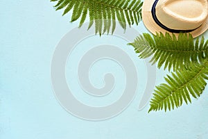 Summer vacation, resort theme. White bucket hat with on blue background with green palm leaves. Flat lay