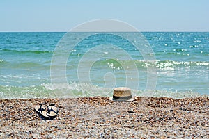 Summer vacation at sea. Hat and flip flops on a sand beach. Sun hat and sandals on beach. Selective focus.