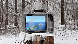 Summer vacation sea scene on the vintage tv in the forest on winter season with snow