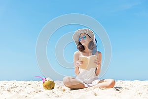 Summer Vacation. Smelling asian women relaxing and reading book on the beach, so happy and luxury in holiday summer, blue sky back