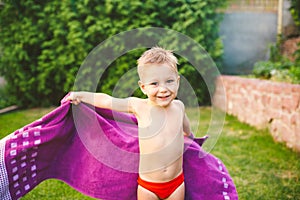 Summer vacation theme. A small 3 year old Caucasian boy playing in the backyard of a house on the grass near a round