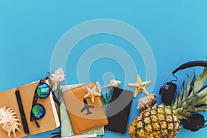 summer vacation and travel flat lay. stylish black phone, passport, sunglasses, map, pineapple with headphones, shells,notebook o