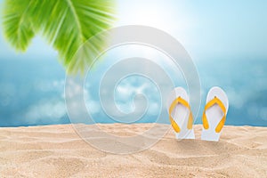 Tropical beautiful seascape view of sand beach with yellow sandals and blurred blue sky with bokeh sunlight in background.