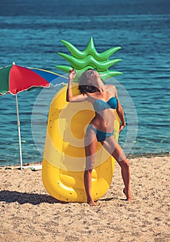 Summer vacation and travel to ocean. summer beach with woman sunbathing at yellow pineapple air mattress.